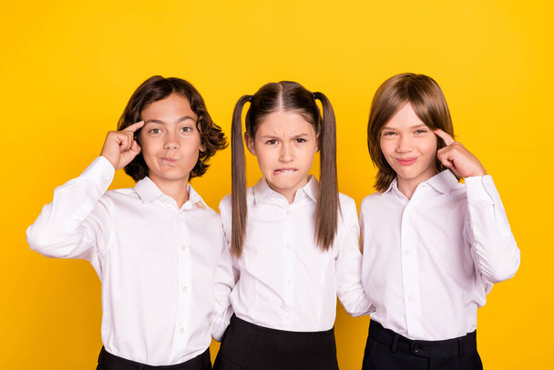 Photo of three minded schoolchildren hard brainstorming wear white shirt isolated yellow color background - Photo, Image