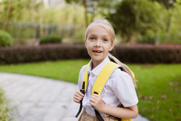 Schoolgirl back to school after summer vacations. Pupil in uniform smiling early morning outdoor.  - Foto, Imagem