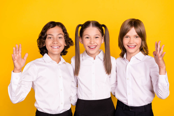 Photo of three cheerful friendly glad nice schoolchildren wear white shirt isolated yellow color background - Foto, afbeelding