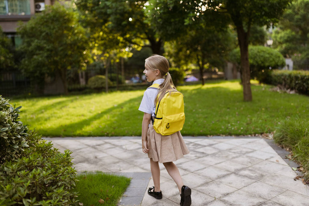 Schoolgirl back to school after summer vacations. Pupil in uniform smiling early morning outdoor.  - Фото, зображення
