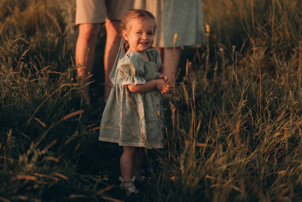 Happy family walks in park at sunset. Mom, dad and baby. Healthy family plays in field. Happy family concept - Photo, Image