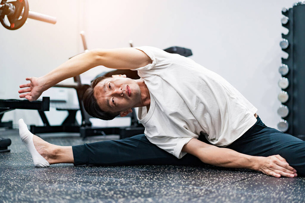 Mężczyzna w średnim wieku robi ćwiczenia rozciągające na siłowni - Zdjęcie, obraz