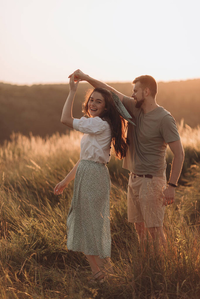 Young happy couple in love hugging and holding hands beautifully in the sunset mountains - Zdjęcie, obraz