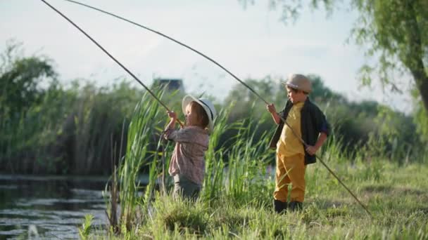 帽子の男の漁師は村の家族の週末に川でロッドと楽しい釣りをしています - 映像、動画