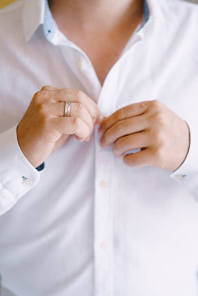 De bruidegom knoopt de knopen op het witte shirt. Close-up - Foto, afbeelding