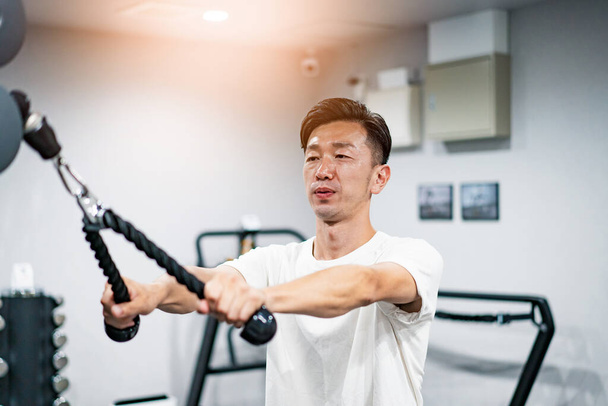 Азіатський чоловік середнього віку тренується в тренажерному залі
 - Фото, зображення