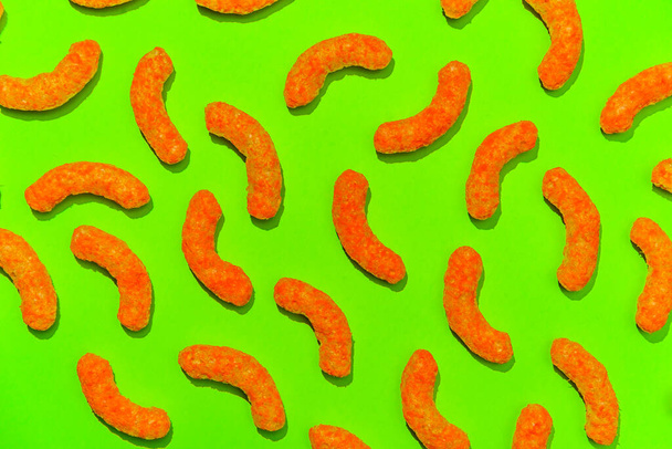Cheddar cheese flavored puffed corn curls snack on neon colorful background - Photo, Image