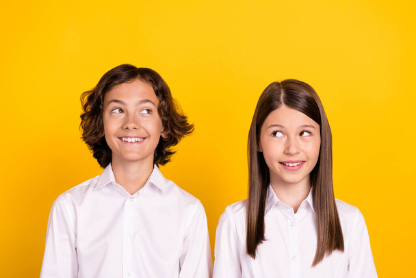 Photo of cheerful schoolkids look empty space think ideas wear white shirt isolated yellow color background - Foto, Imagem