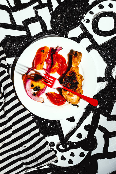 Marinated peach chicken legs on black and white abstract background with floating red fork - Photo, Image