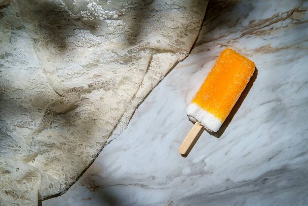 Verfrissend bevroren dessert Oranje en roomijs knallen op een stokje - Foto, afbeelding