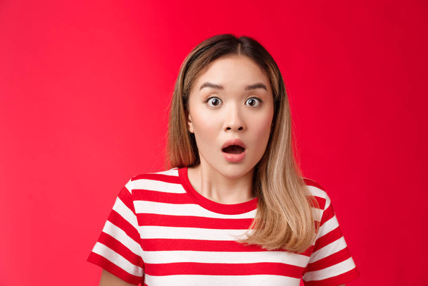 Close-up shocked alarmed speechless asian blond woman drop jaw, gasping impressed, hear shocking stunning rumor, open mouth astonished, react shook news, stand red background - Photo, Image