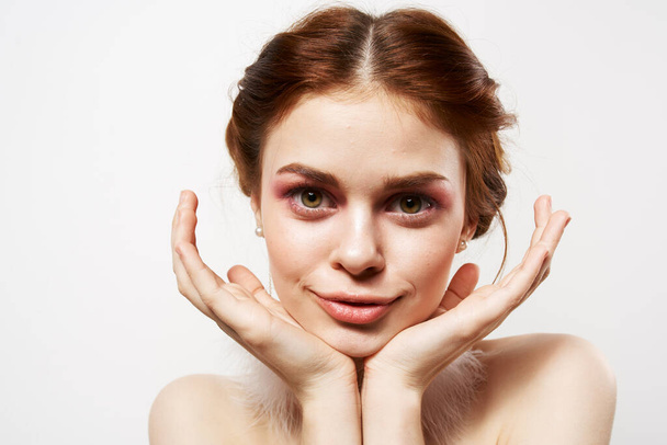 mooie vrouw met blote schouders heldere make-up pluizig oorbellen cosmetica Glamor - Foto, afbeelding
