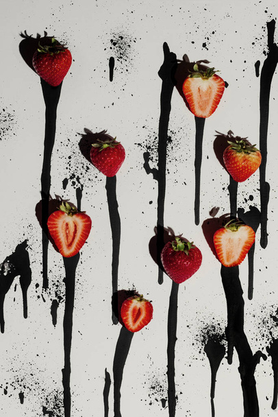Fresh strawberries on abstract black and white paint drip background - Fotó, kép