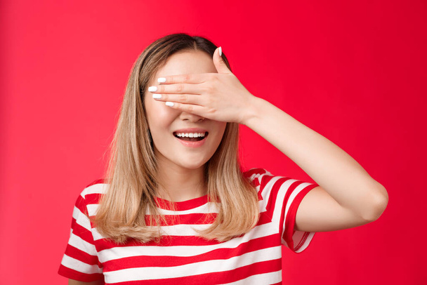 Close-up lucky cute asian blond woman smiling broadly count ten promise not peek, cover eyes with palm grinning awaiting surprise b-day party gift, stand red background anticipating - Photo, Image