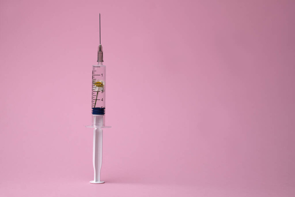 Creative beauty injection concept. Syringe with toxin and flowers inside on pastel pink background, 2019-nCoV or COVID-19 vaccine. Corona virus outbreak. Epidemic virus Respiratory Syndrome. - Fotó, kép