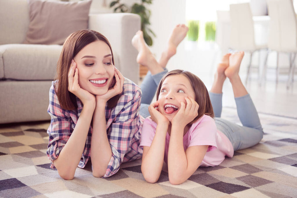 Portrait of two attractive cheerful girls lying on floor having fun good mood fooling at home flat indoors - Foto, Imagem