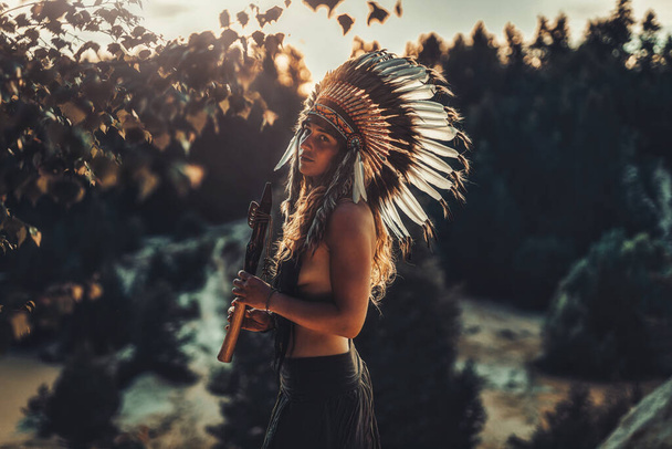 beautiful shamanic girl playing on shaman flute in the nature. - Photo, Image
