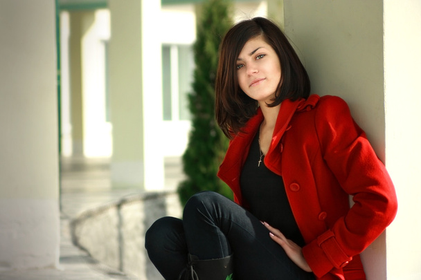 güzel bir oturma içinde kırmızı palto genç kızdır - Fotoğraf, Görsel