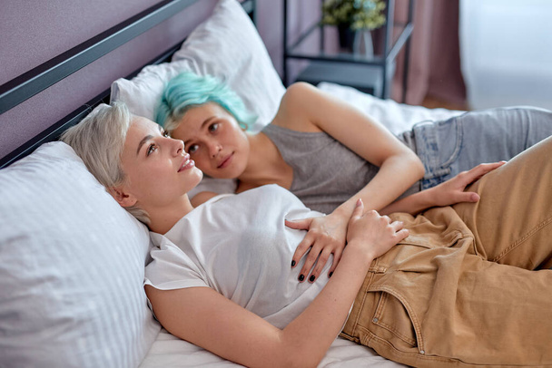 Calm beautiful lesbian or friends having talak, enjoying rest on bed at home. - 写真・画像