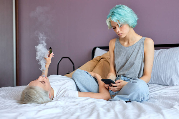 Two pretty best friends forever girlfriend talk, relaxing, smoking and surfing the Net - Zdjęcie, obraz