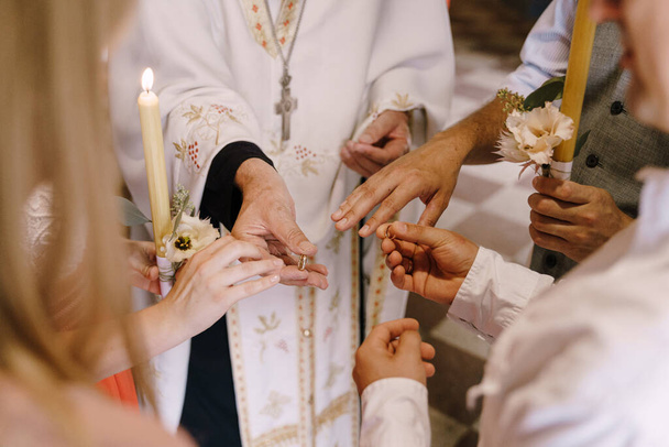 Priester reicht Braut und Bräutigam die Ringe mit Kerzen in der Hand - Foto, Bild