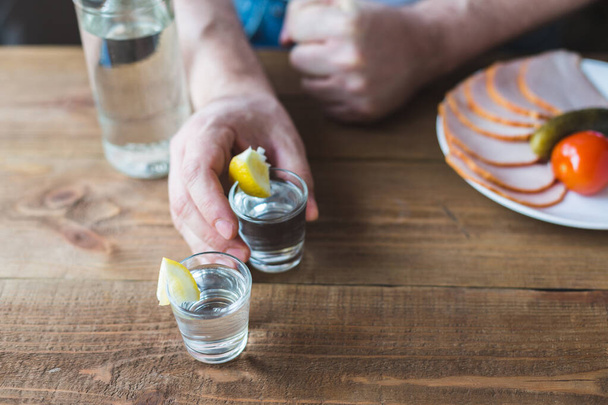 Schnapsgläser Wodka auf einem Holztisch, Flasche und einen Teller mit Schinken - Foto, Bild