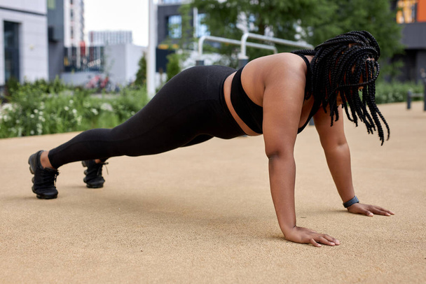 Sporty fat woman in black sportswear, practicing fitness, doing Push ups or press ups - Fotoğraf, Görsel