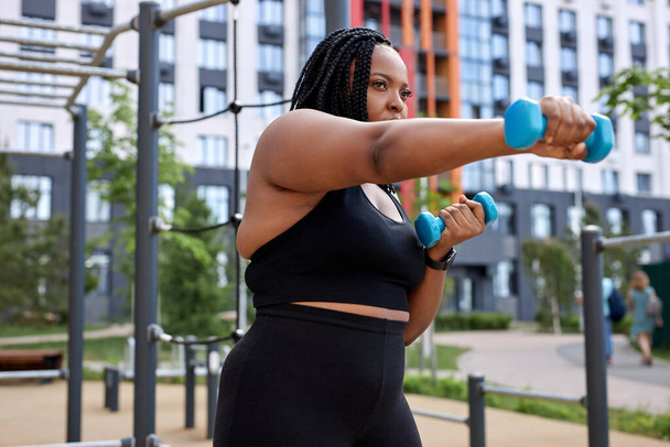 healthy overweight fat african woman exercising with dumbbells, outdoor sport activity - Foto, imagen