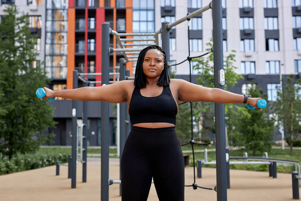 Healthy young afro american woman lifting weights outdoors in public sports ground - Φωτογραφία, εικόνα
