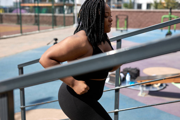 overweight young african woman foing fitness exercises on stairs outdoors. weight loss - Foto, Imagem