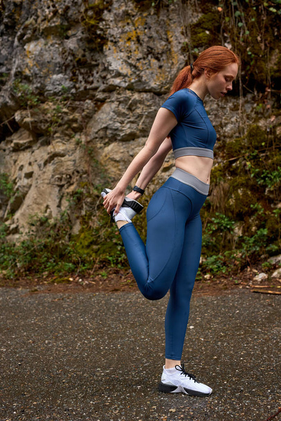 Side view full-length portrait of fitness lady stretching legs, warm up muscles - 写真・画像