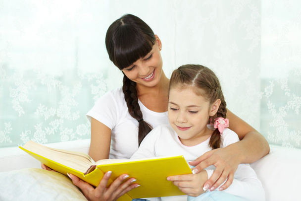 Menina e sua mãe lendo livro
 - Foto, Imagem
