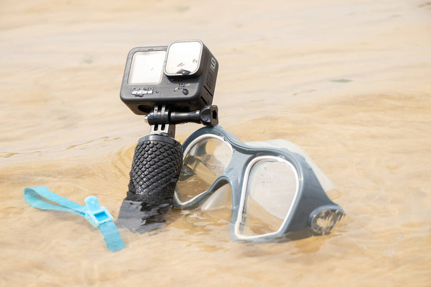 Ucraina Dnipro 05.08.2021 - Macchina fotografica e maschera GoPro HERO 9 per le immersioni in spiaggia in acqua in riva al lago, action camera sul lago - Foto, immagini