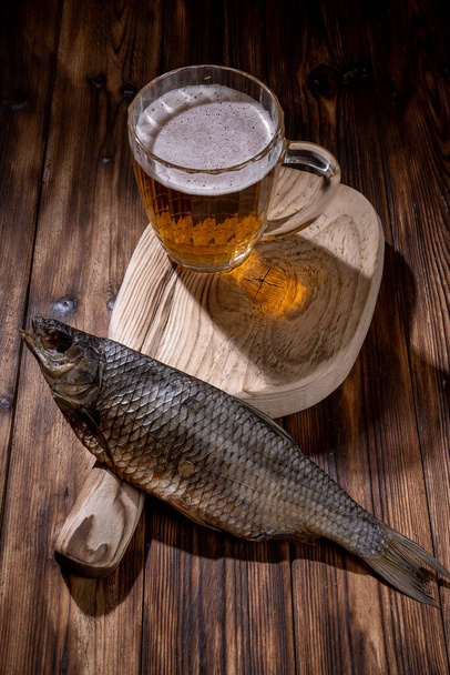 Beer with dried fish and snacks on wooden table. - Foto, afbeelding