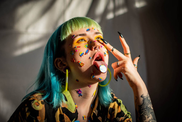 Closeup fashion portrait young pretty beautiful girl with green and blue hair. Beautiful fashion girl with luxury professional makeup and funny emoji stickers glued on the face. Young woman - Photo, Image