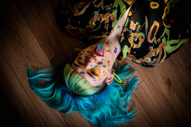 Κοντινό πορτρέτο μόδας νεαρή όμορφη όμορφη κοπέλα με πράσινα και μπλε μαλλιά. Όμορφο κορίτσι της μόδας με πολυτελές επαγγελματικό μακιγιάζ και αστεία αυτοκόλλητα emoji κολλημένα στο πρόσωπο. Νεαρή γυναίκα - Φωτογραφία, εικόνα