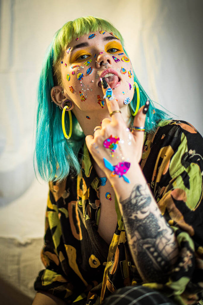 Closeup fashion portrait young pretty beautiful girl with green and blue hair. Beautiful fashion girl with luxury professional makeup and funny emoji stickers glued on the face. Young woman - Foto, afbeelding
