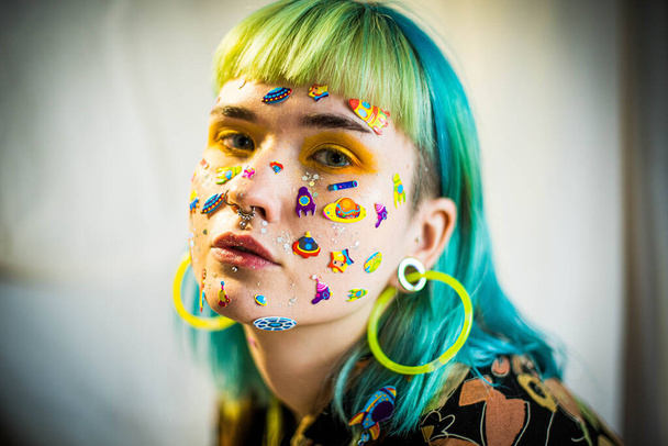 Closeup fashion portrait young pretty beautiful girl with green and blue hair. Beautiful fashion girl with luxury professional makeup and funny emoji stickers glued on the face. Young woman - Foto, immagini