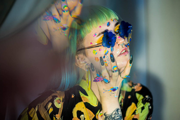 Closeup fashion portrait young pretty beautiful girl with green and blue hair. Beautiful fashion girl with luxury professional makeup and funny emoji stickers glued on the face. Young woman sunglasses - Fotó, kép