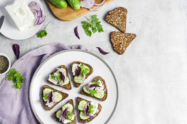 Canapes with toasted bread with sunflower and flax seeds, feta cheese, cucumber and onion - Photo, Image
