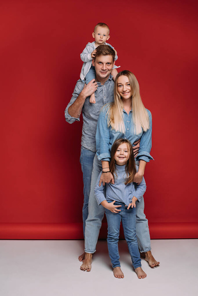 Glückliche Familie mit Sohn und Tochter auf rotem Hintergrund. - Foto, Bild