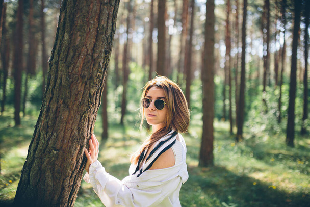 Young beautiful hippie woman walks in the summer forest laughs dances and enjoys life and nature - Фото, зображення