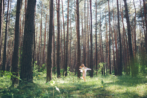 Young beautiful hippie woman walks in the summer forest laughs dances and enjoys life and nature - Valokuva, kuva