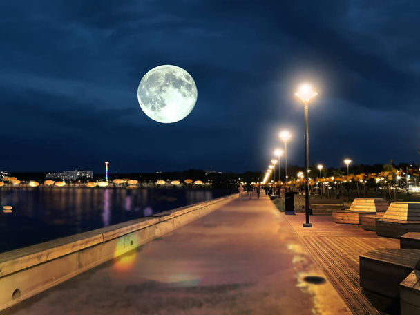 romántico verano noche paseo marítimo a pie y relajarse ciudad puerto calle luz borrosa en el agua de mar luna llena en el cielo azul oscuro Tallinn Reidi tee - Foto, imagen