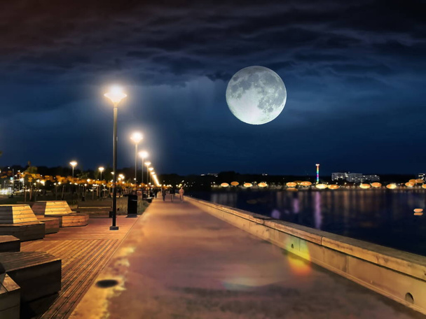 Panorama in der Nacht Stadt von der Nachtpromenade am Meer Menschen gehen und entspannen Stadt Hafen Straßenlicht verschwommen am Meer Wasser Vollmond am dunkelblauen Himmel Tallinn Reidi Tee - Foto, Bild