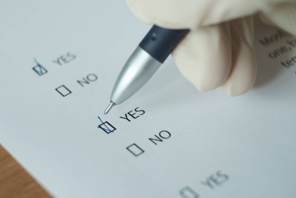 Une feuille blanche du questionnaire, la réponse "oui" est mise avec un stylo. Image floue. - Photo, image