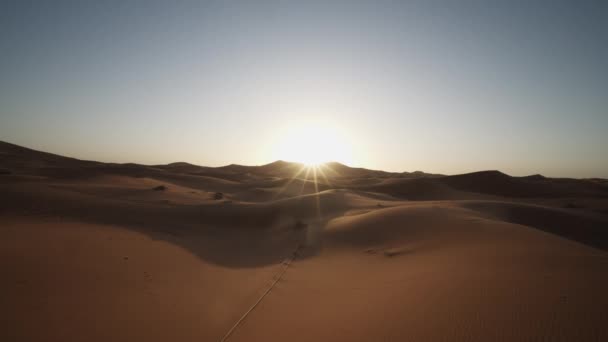 Liukumäki ja pannulla laukaus hiekkadyynit autiomaassa. Näkymä nousevaa aurinkoa vastaan. Äärimmäisen kuiva ja hedelmätön maisema. Marokko, Afrikka - Materiaali, video