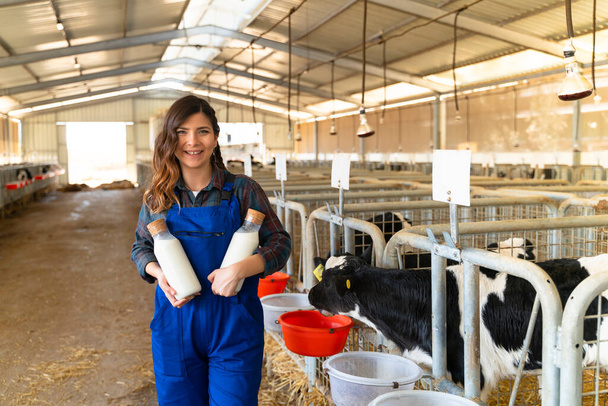 Farmer standing with two bottles of fresh milk in hands on farm - Photo, image
