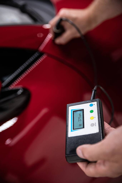 Man mechanic checking car paint thickness with electronic meter - Foto, afbeelding