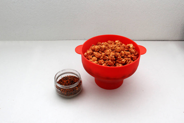 Pokryty chili popcorn wyprodukowany w czerwonym pojemniku mikrofalowym - Zdjęcie, obraz